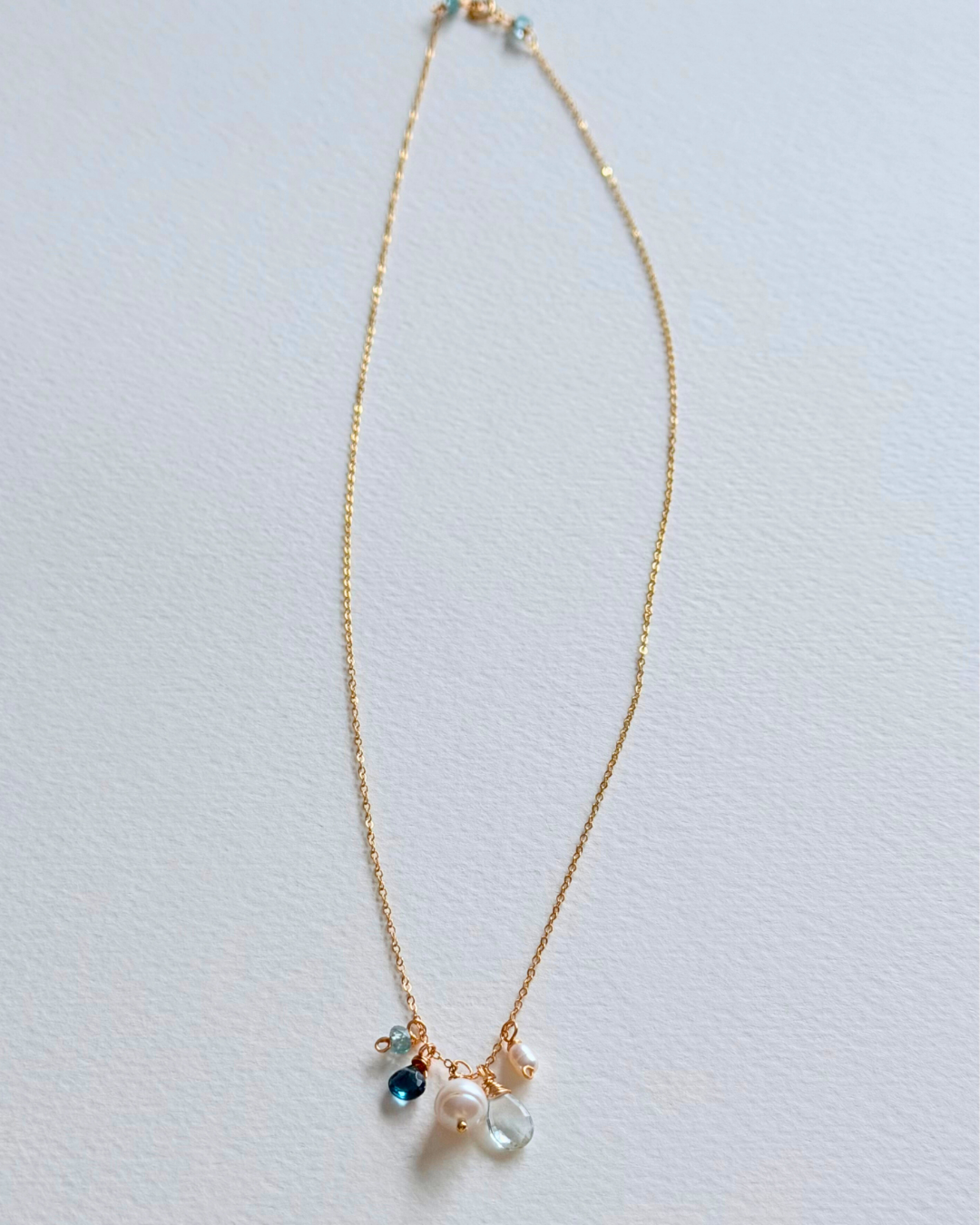 Gold necklace with small pendants on a light gray background