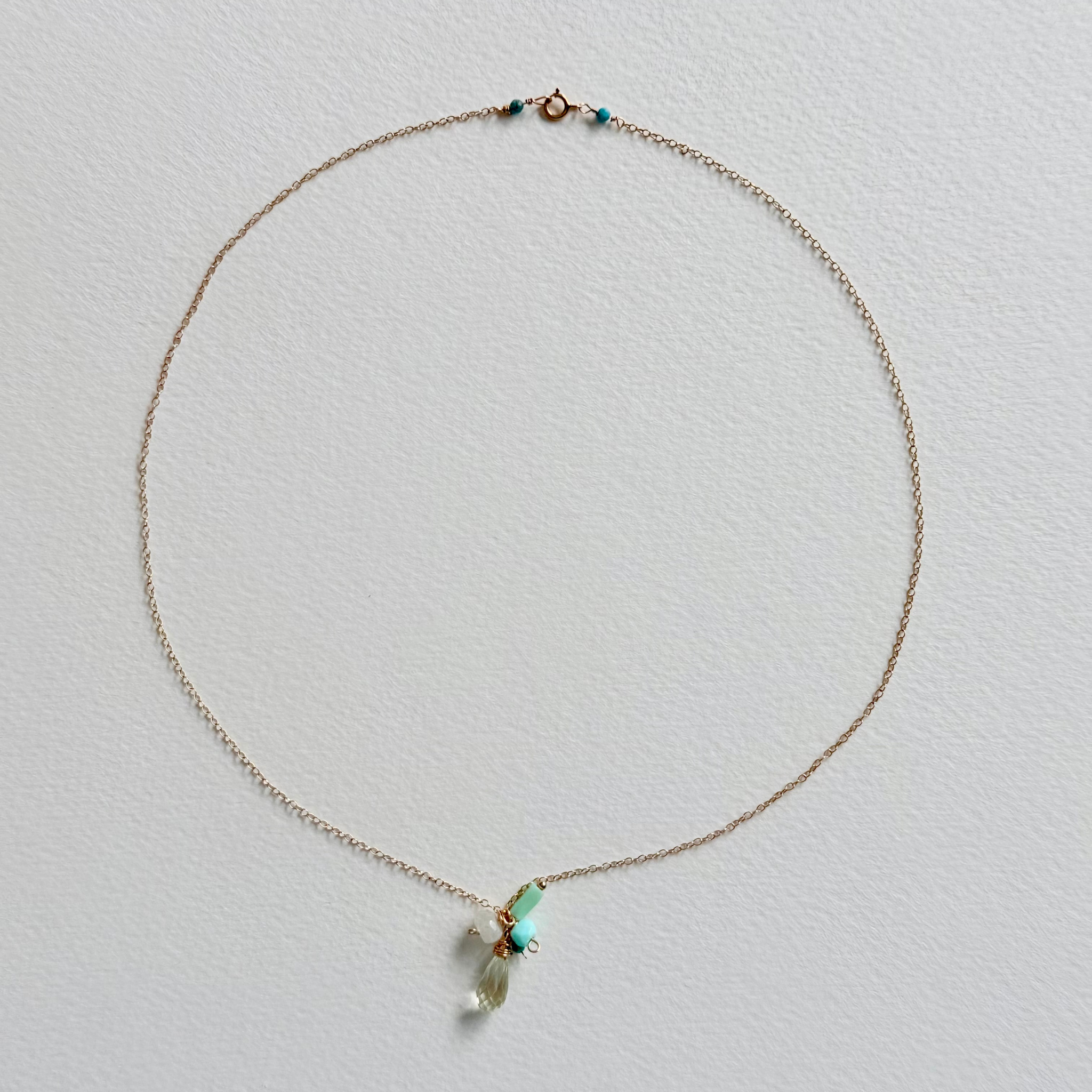 Delicate necklace with a small pendant on a light gray background