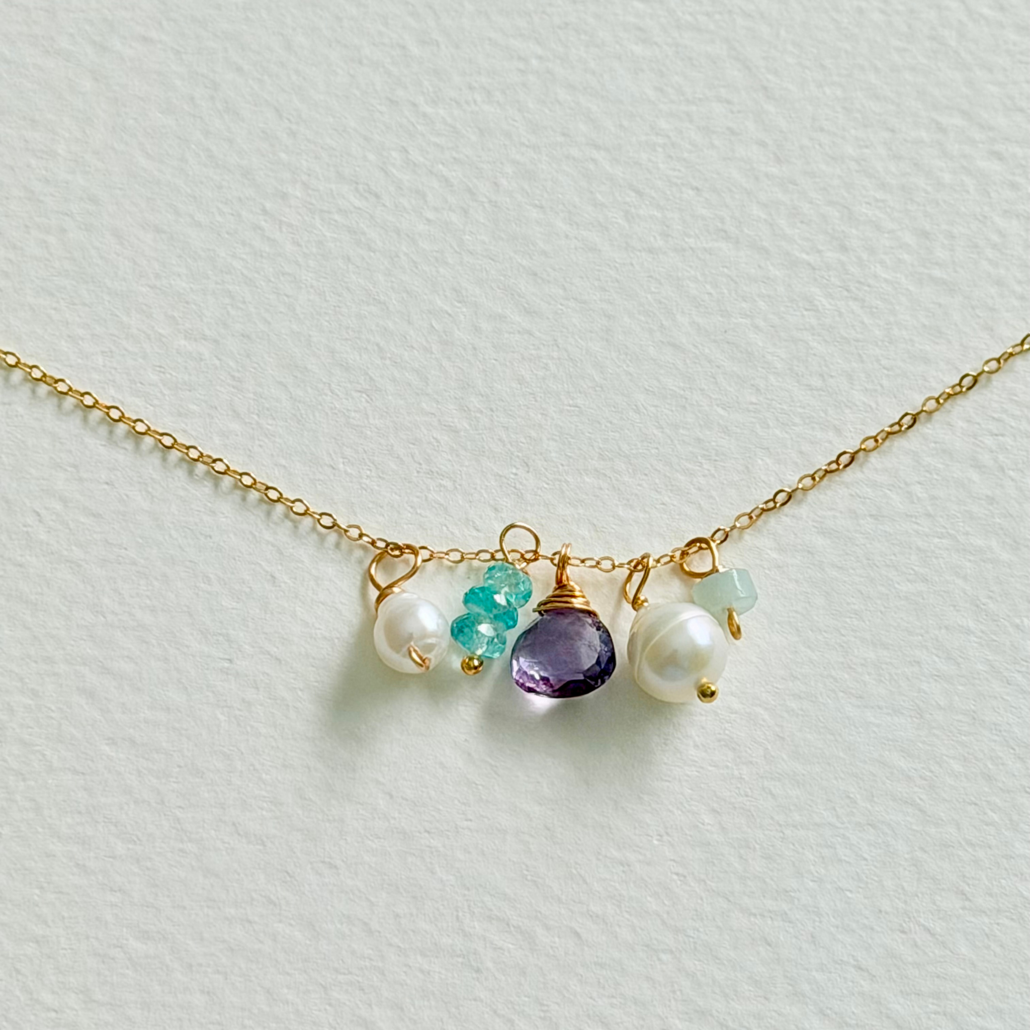 Necklace with gold chain and colorful beads on a light background