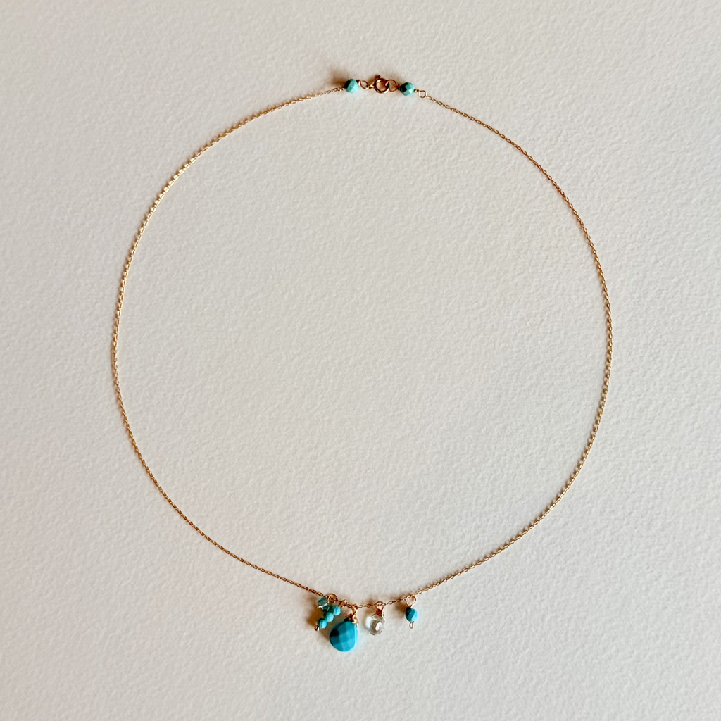 Delicate necklace with turquoise beads on a light background