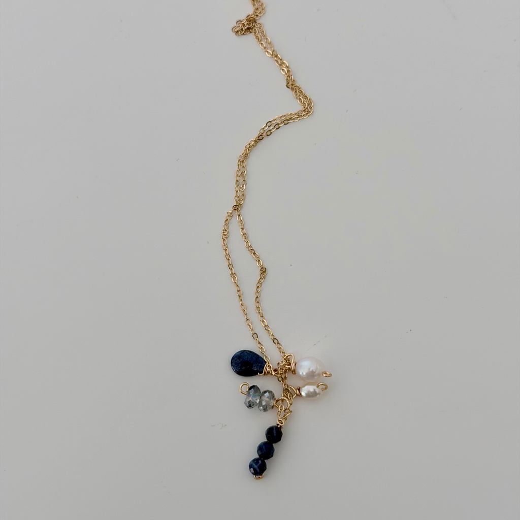 Gold necklace with blue and white beads on a light gray background