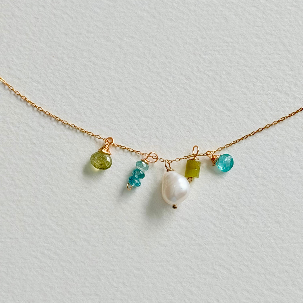 Necklace with gold chain and colorful beads on a light gray background