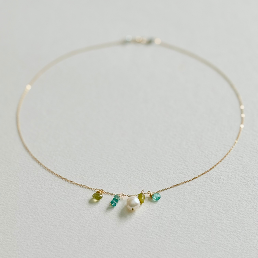Delicate gold necklace with small beads on a light gray background