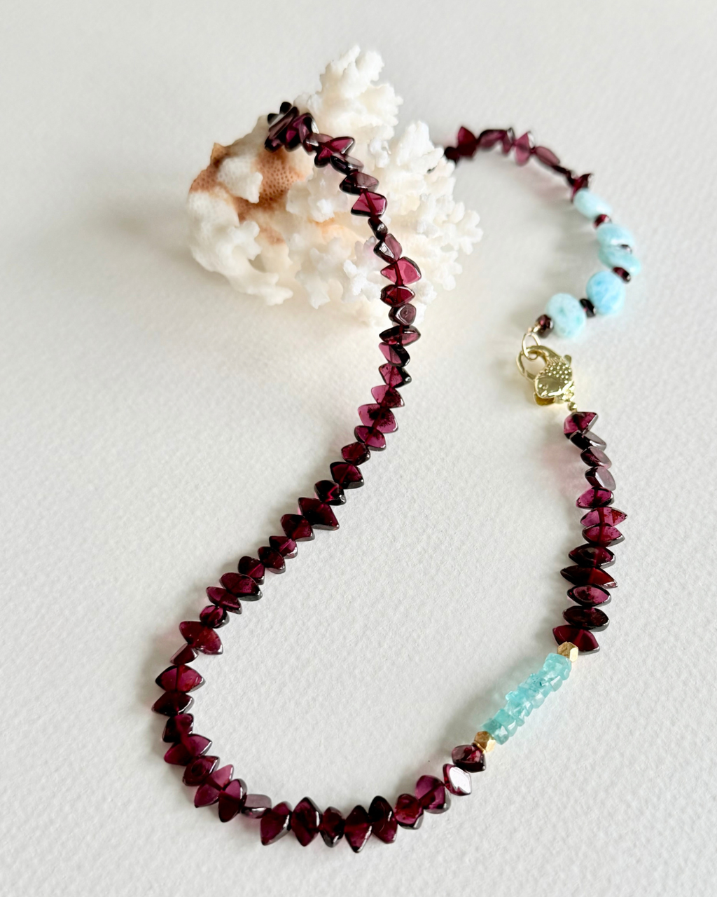 Close-up of Deep Water garnet, larimar and aquamarine necklace with koi fish clasp