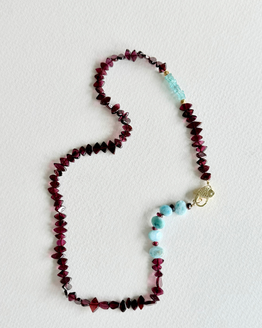 Deep Water garnet and larimar gemstone necklace displayed on light background