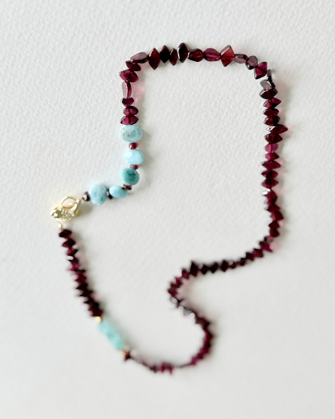 6. Deep Water garnet, larimar and aquamarine necklace styled on textured white background