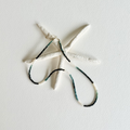 A white starfish-shaped wall hanging with a beaded necklace draped across it, set against a plain white textured background.