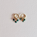 Gold hoop earrings with green beads on a light gray background