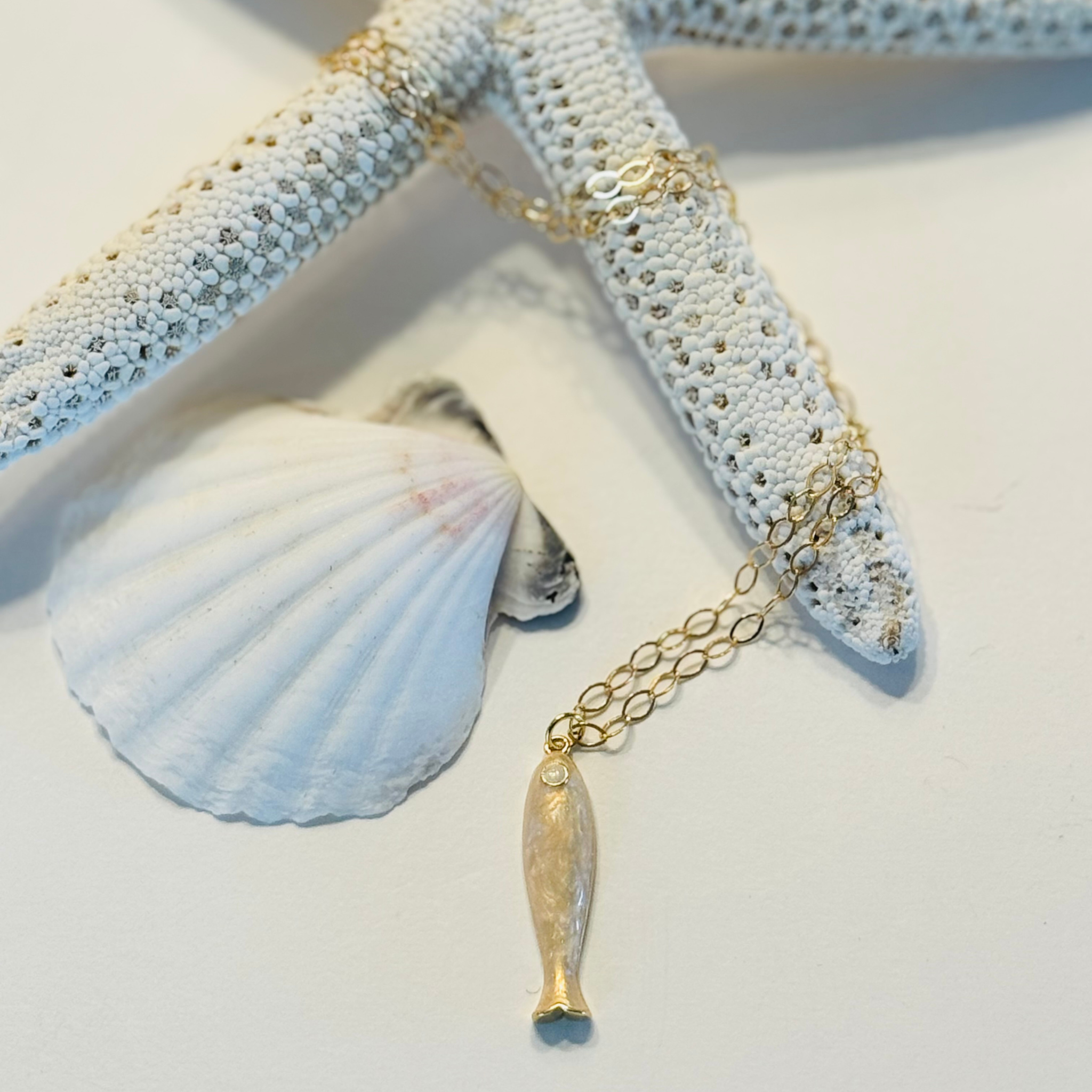 Gold necklace with a pendant on a starfish and shell background