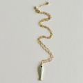 Gold chain necklace with a fish pendant on a light gray background