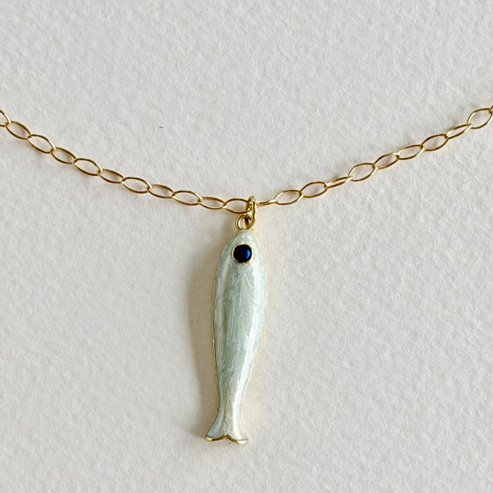 Fish-shaped pendant on a gold chain against a light background
