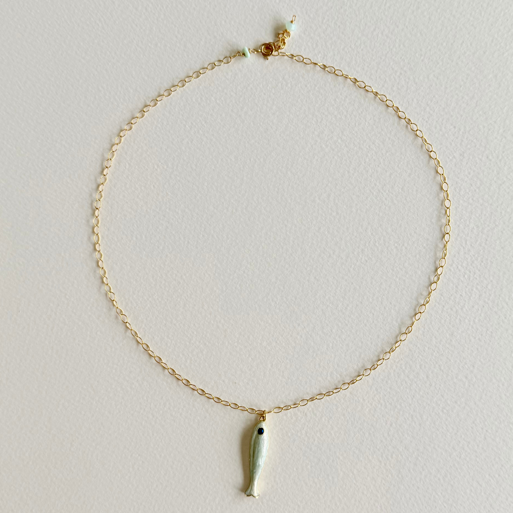 Gold necklace with a small pendant on a light gray background