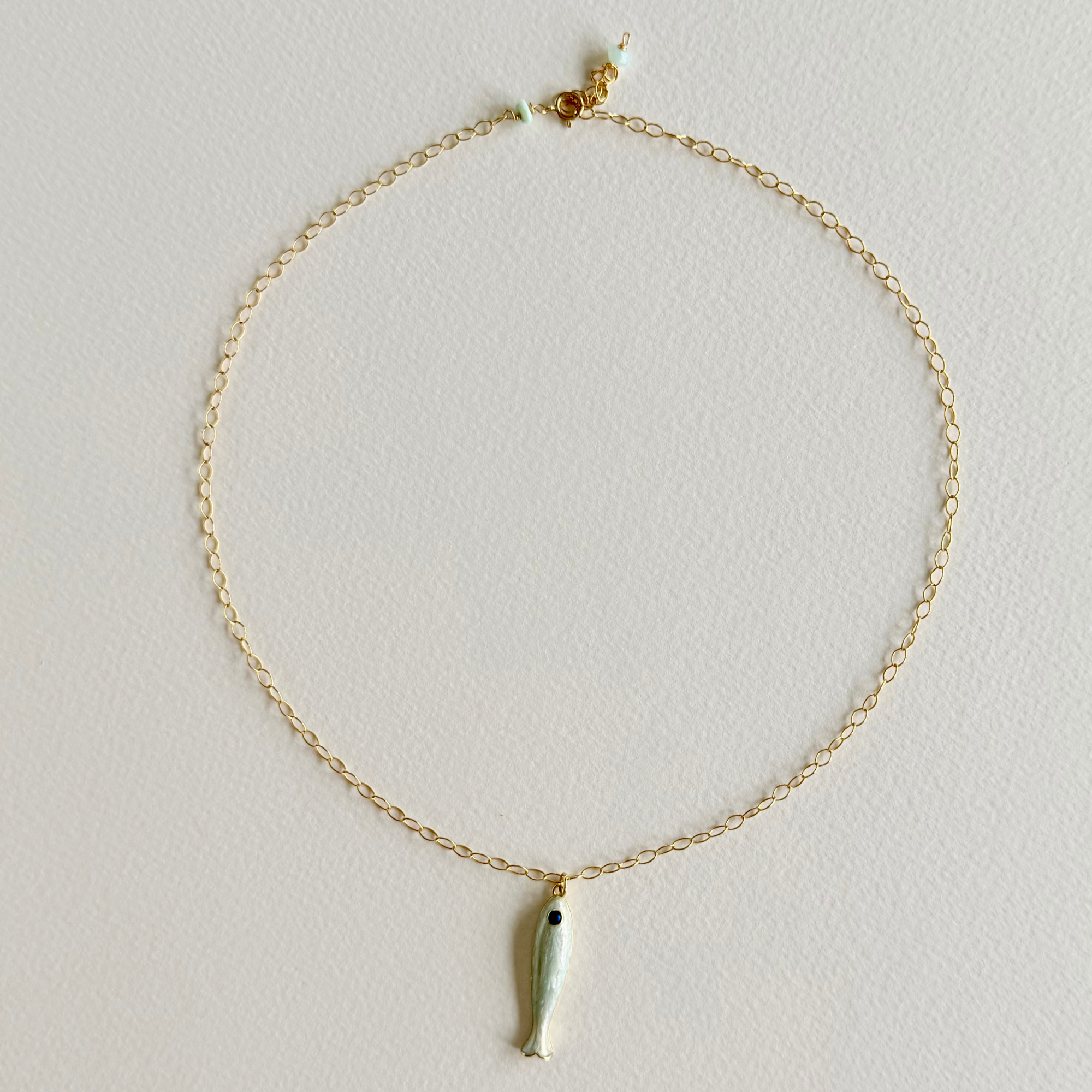 Gold necklace with a small pendant on a light gray background
