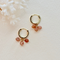 Gold hoop earrings with pink gemstones on a white background