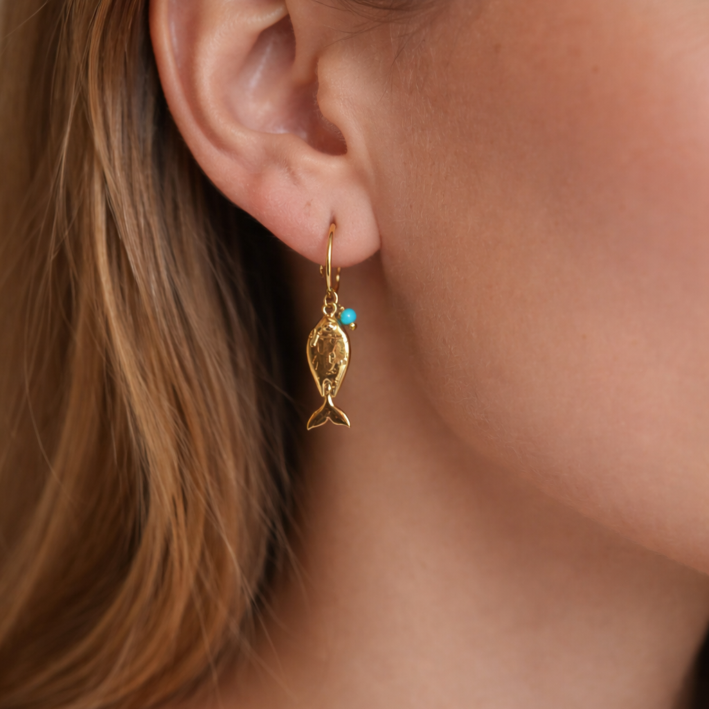 Close-up of a person wearing a gold earring with a turquoise stone.