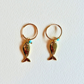 Gold fish-shaped earrings on a white background