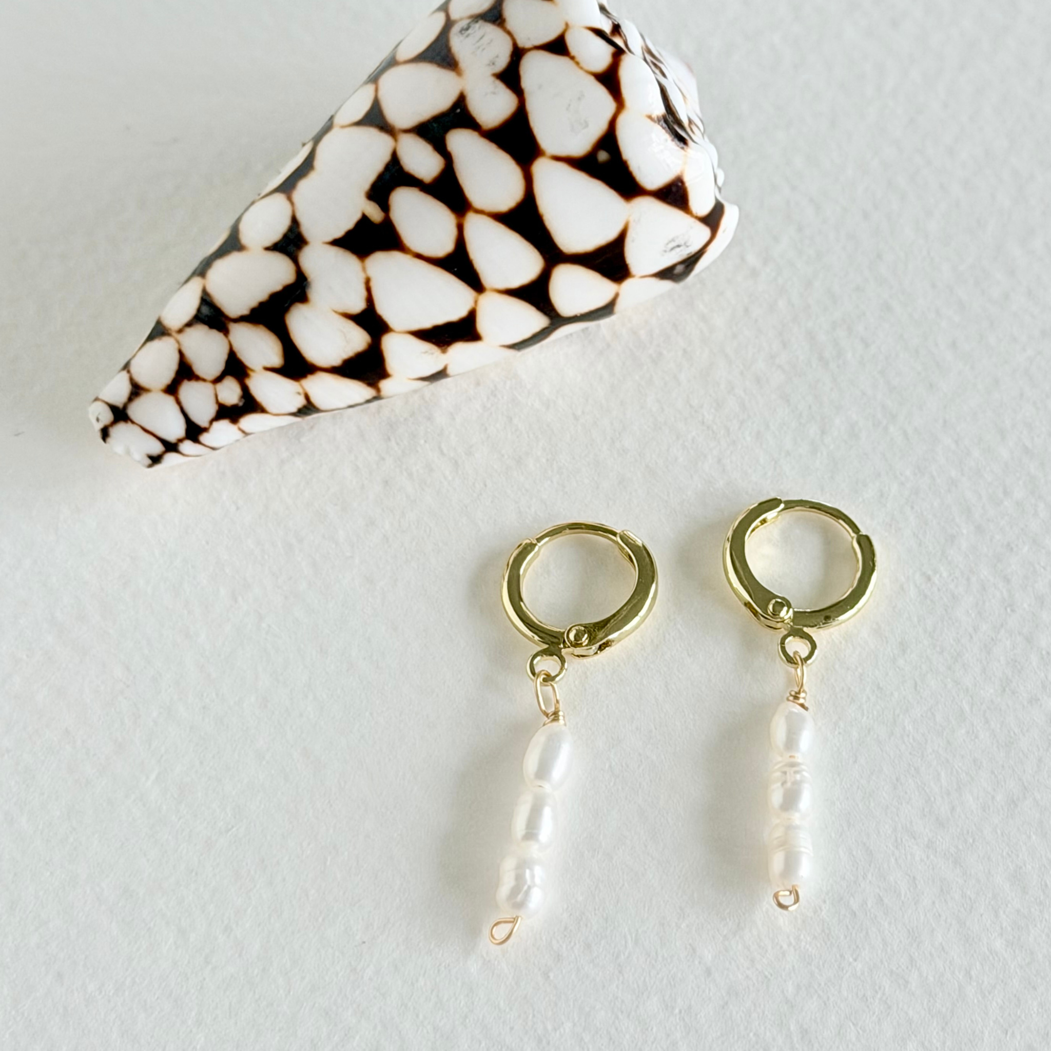 Gold hoop earrings with pearl drops on a white background