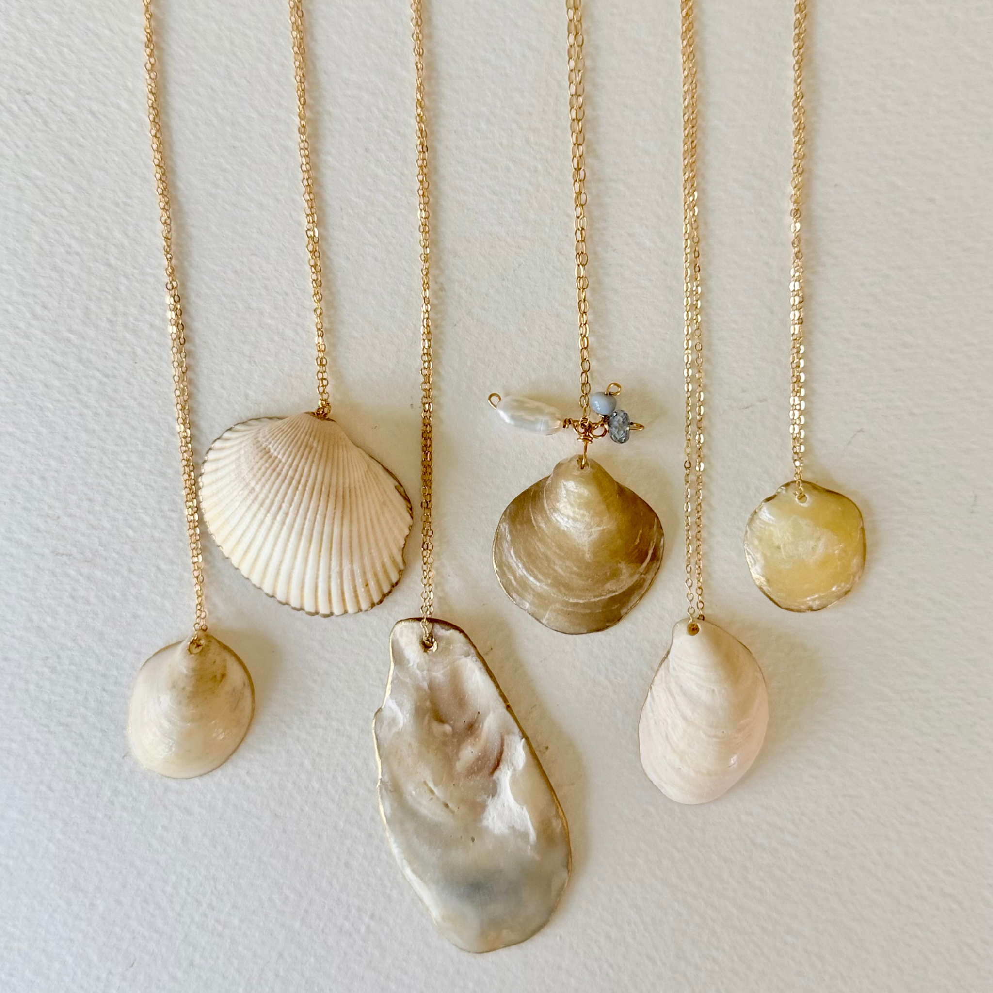 Set of shell necklaces on gold chains against a light background