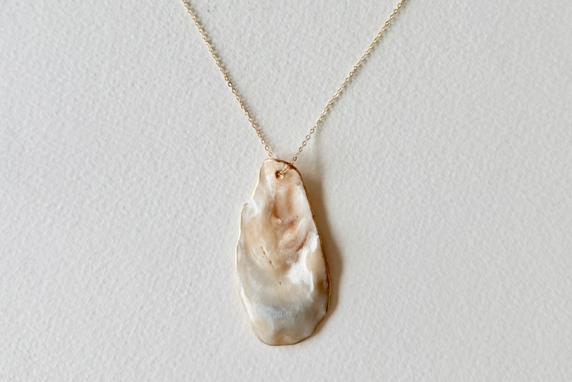 Necklace with a large, irregularly shaped pearl pendant on a light gray background