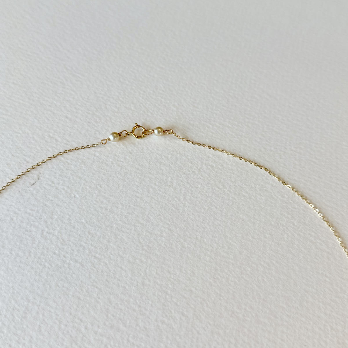 Gold necklace on a light gray background