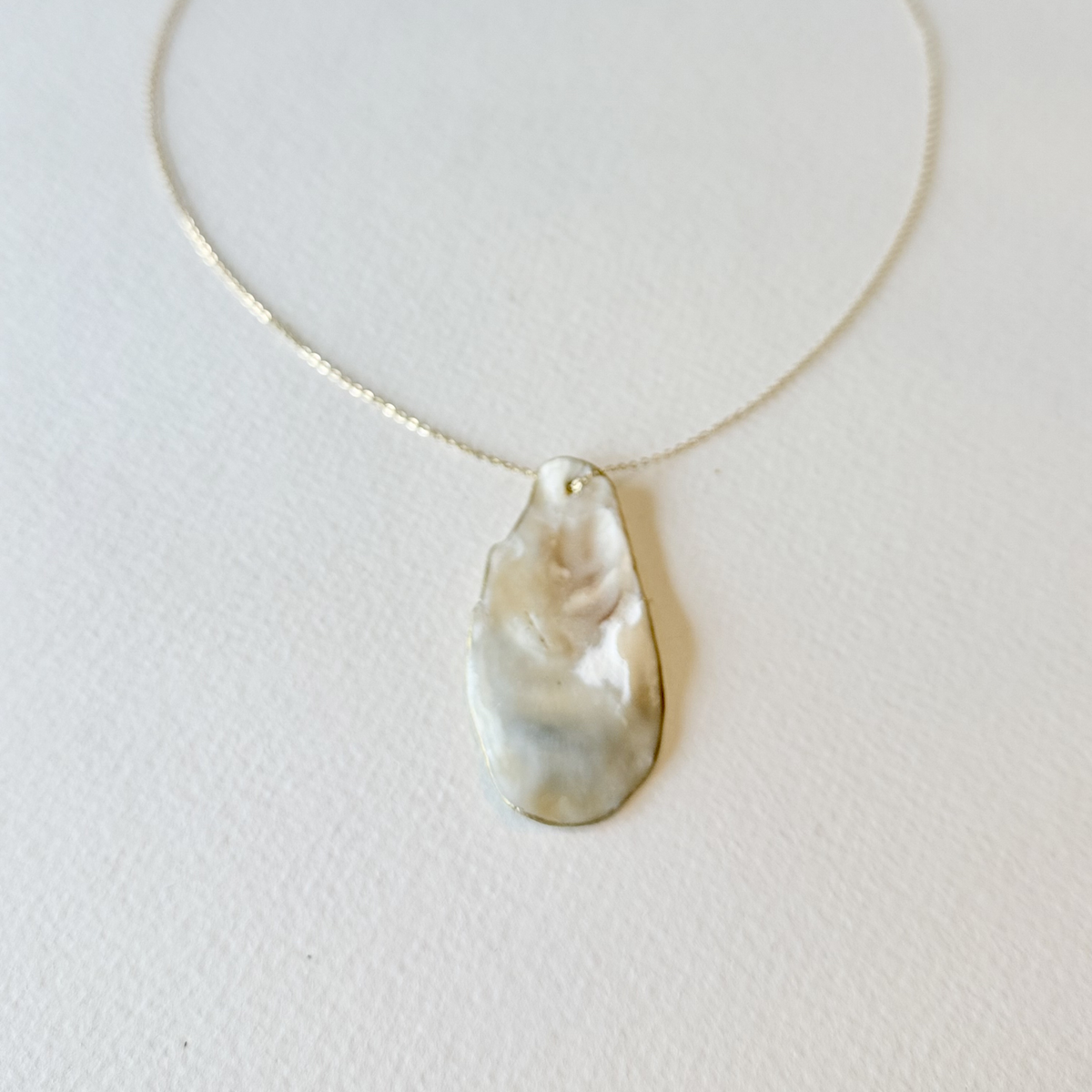 Necklace with a large pearl pendant on a light gray background