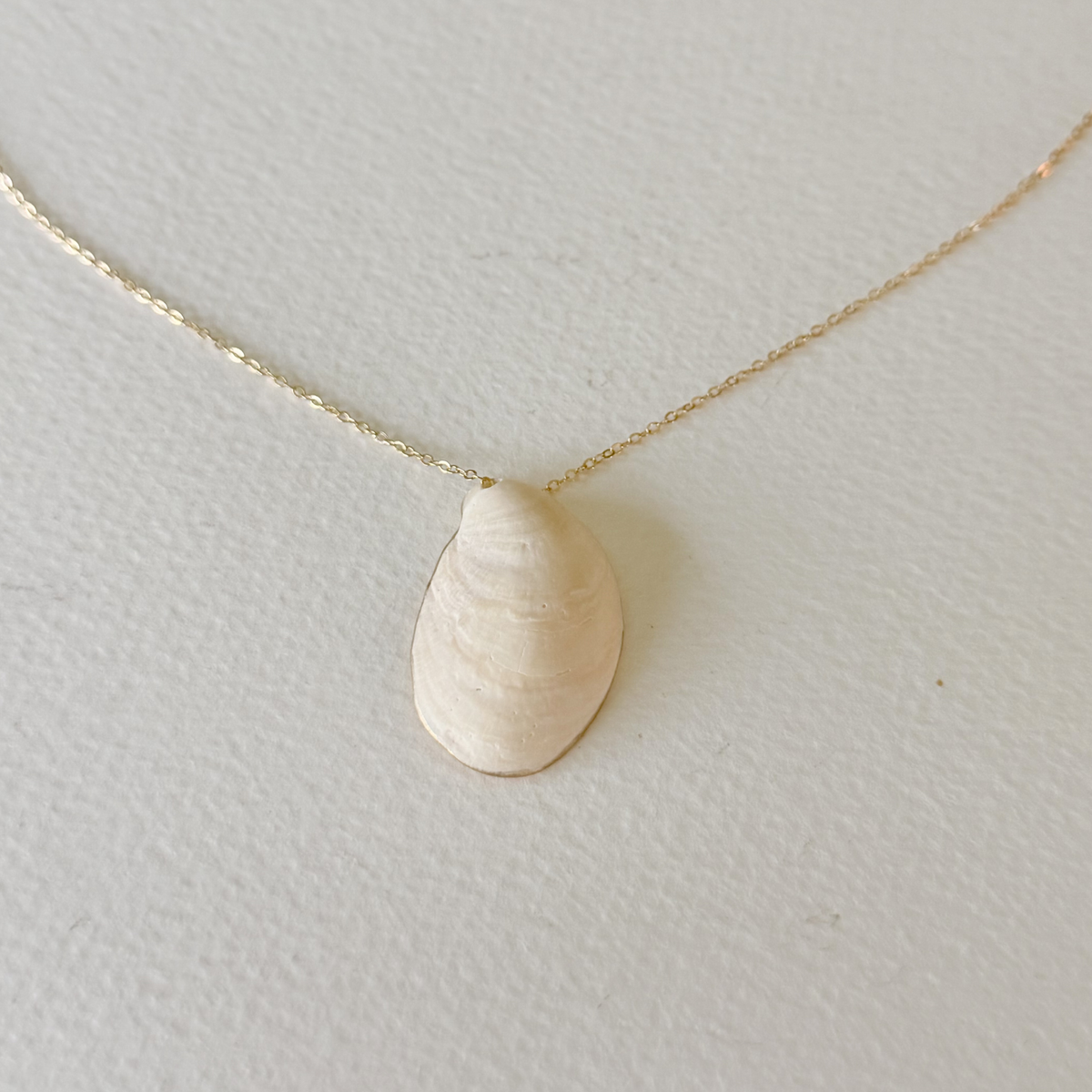 Gold teardrop pendant necklace on a light gray background