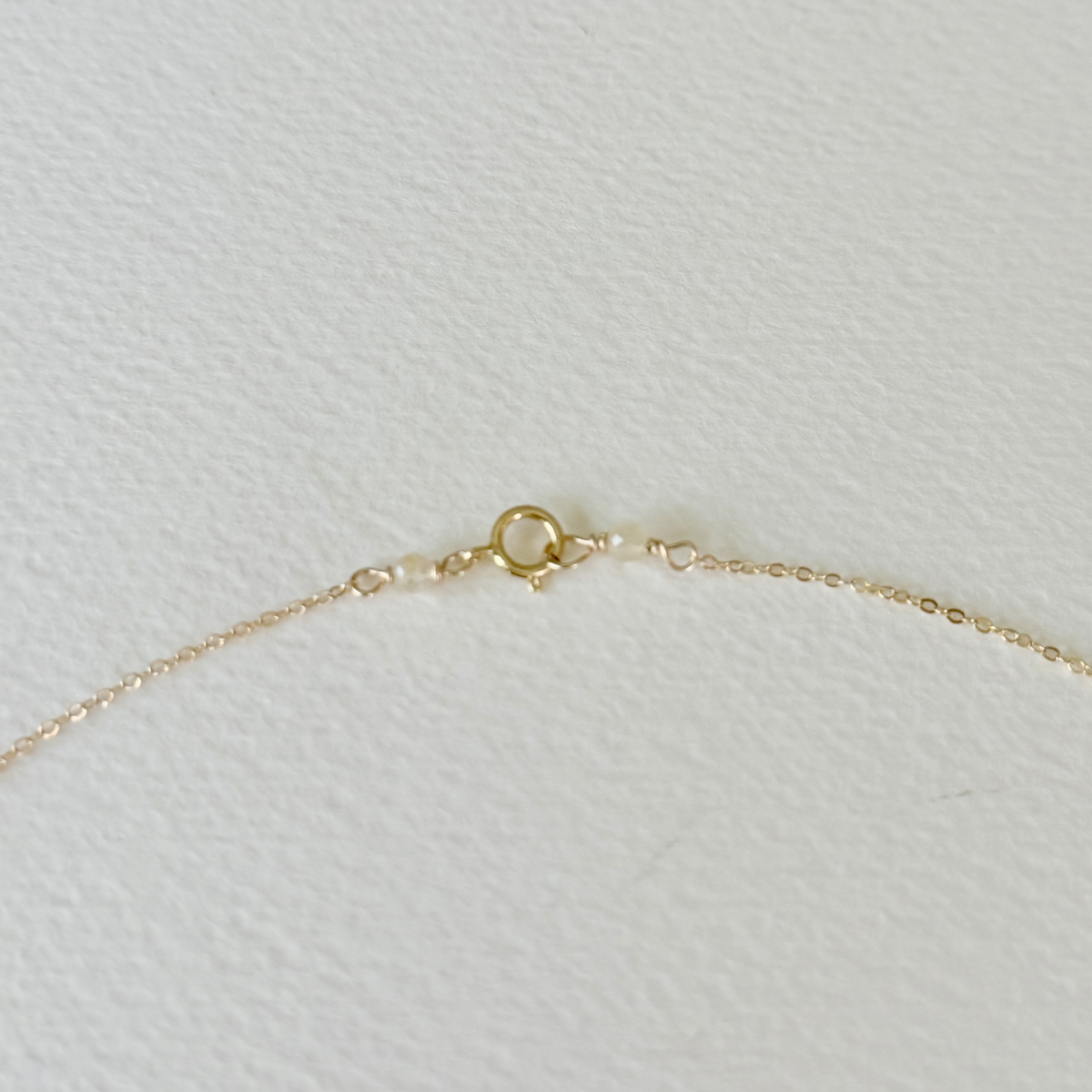 Close-up of a gold chain with clasp on a light gray textured background