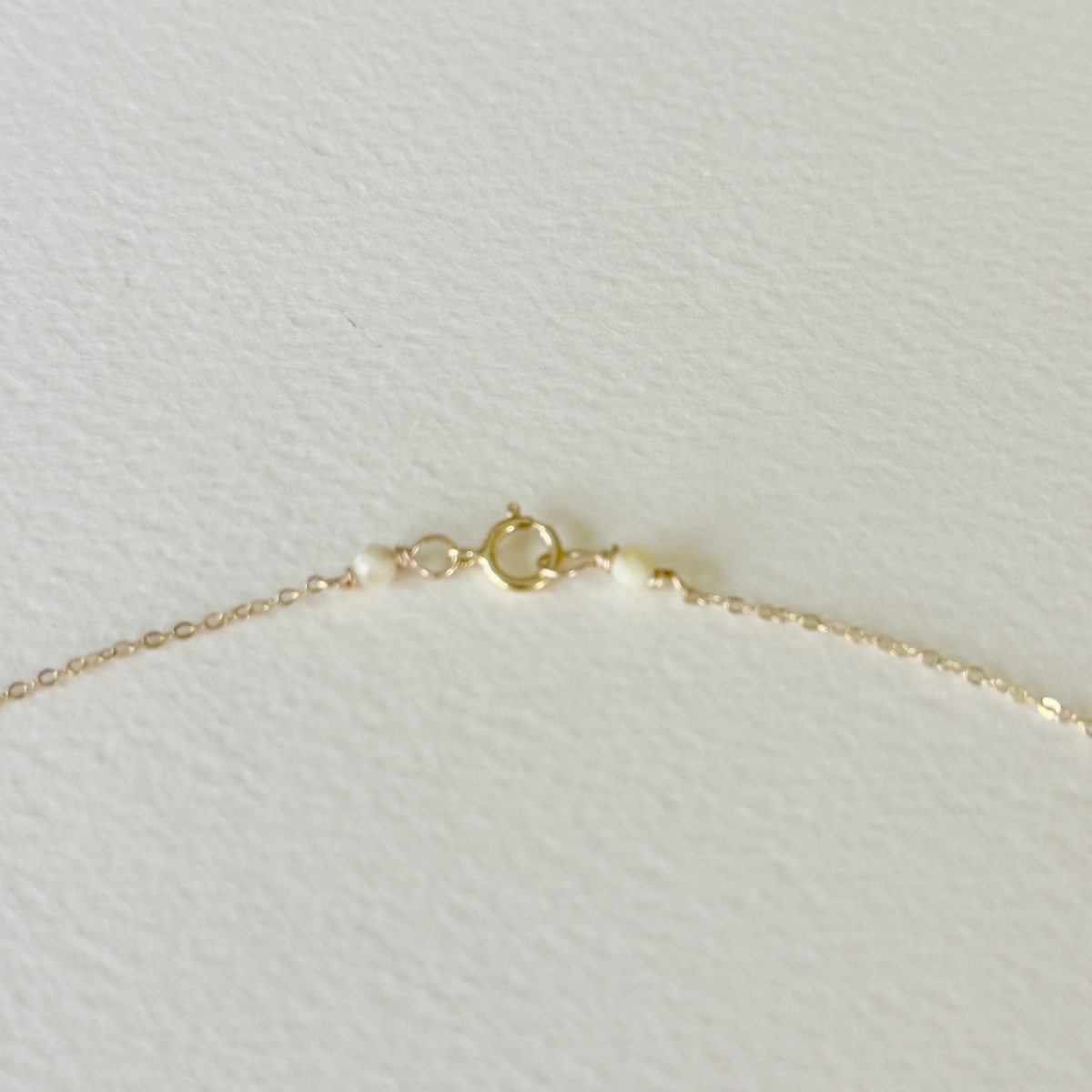 Gold necklace on a light gray textured background