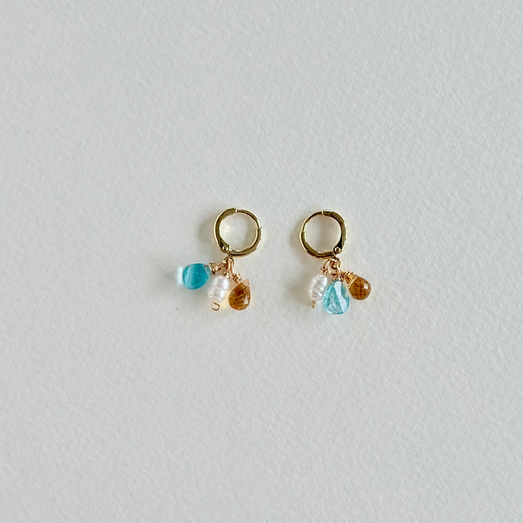 Pair of gold earrings with colorful beads on a light gray background