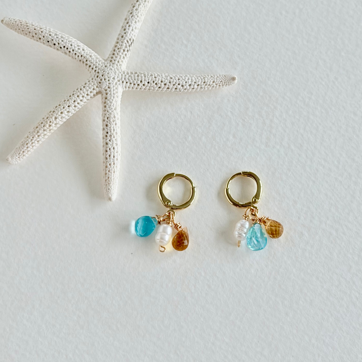 Pair of gold hoop earrings with colorful beads on a light gray background