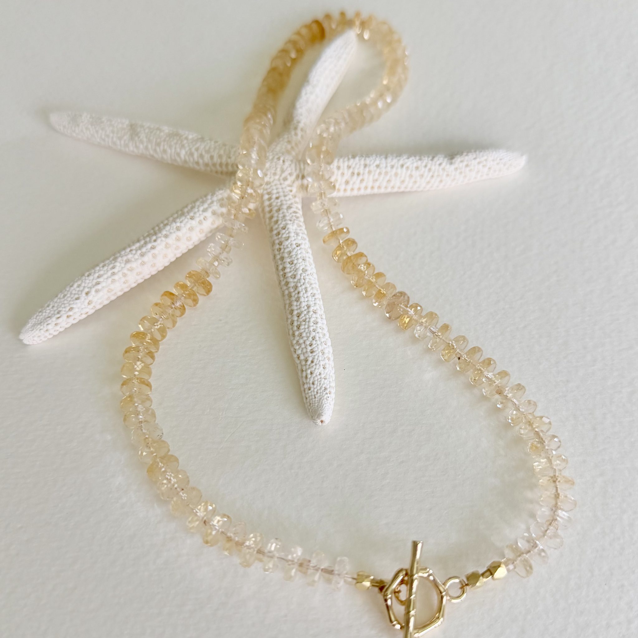 Golden Hour Citrine Necklace handcrafted with natural faceted citrine gemstones in a champagne-to-honey ombré and finished with a 14k gold-filled toggle clasp styled on a starfish.