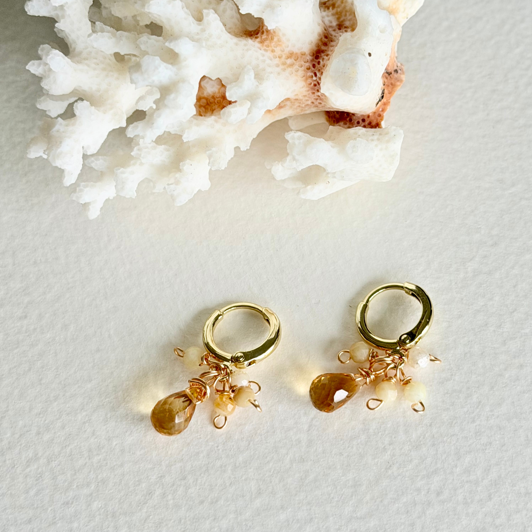 Gold earrings with small charms on a light background