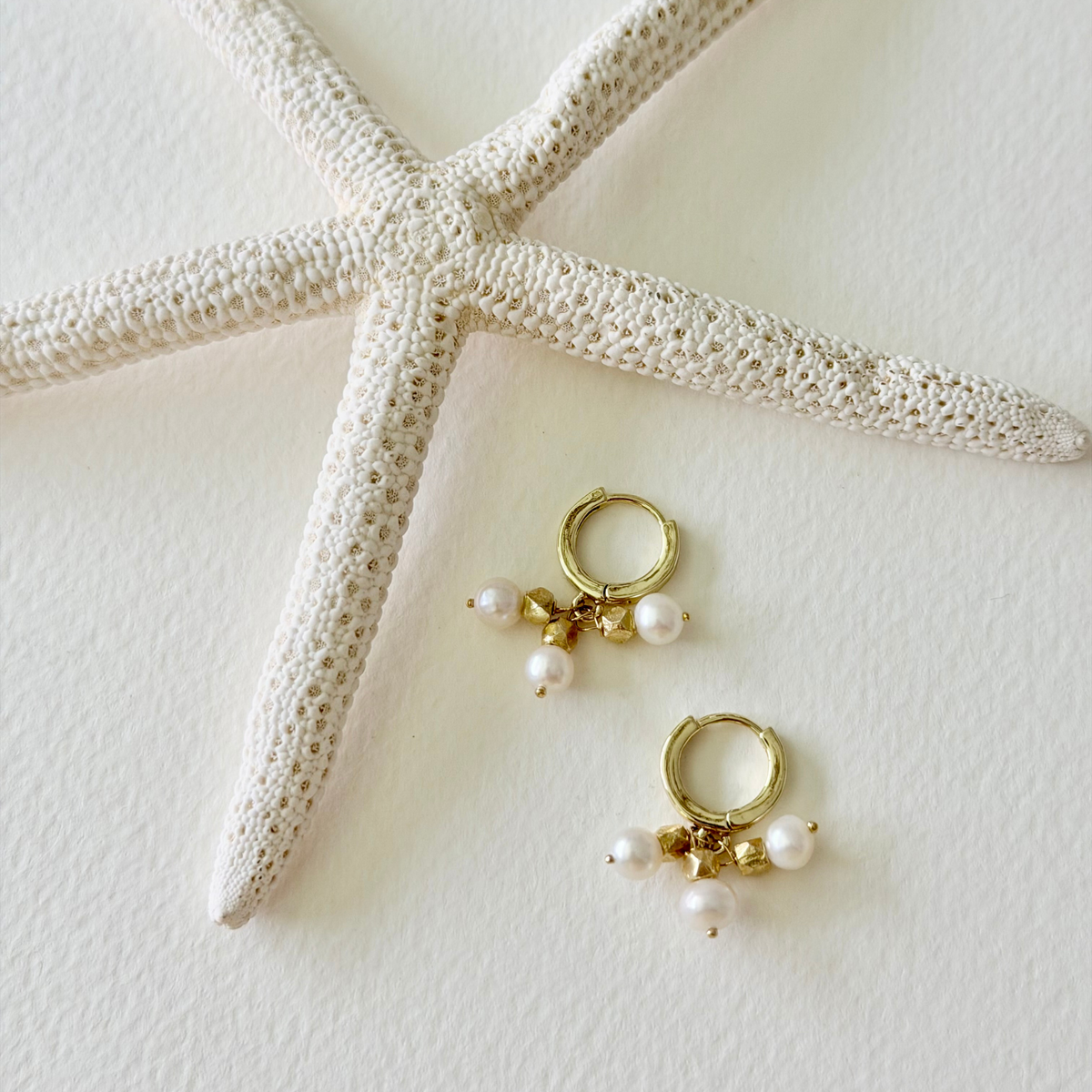 pearl and gold nugget earrings on light background 