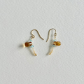 A pair of small gold-tone dangle earrings with citrine and light blue natural zircon beads, displayed on a textured off-white background.