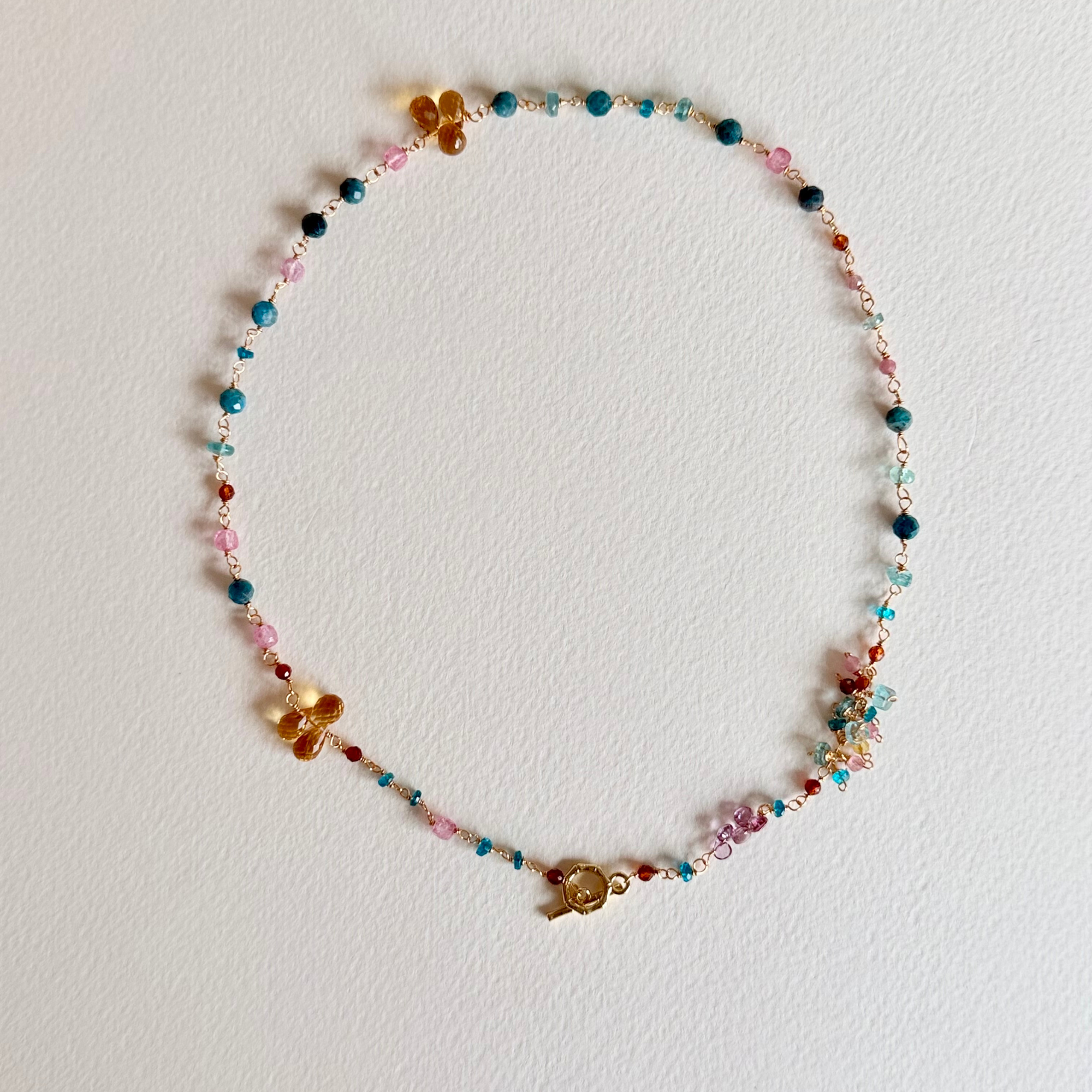 Colorful beaded necklace with floral charms on a light gray background