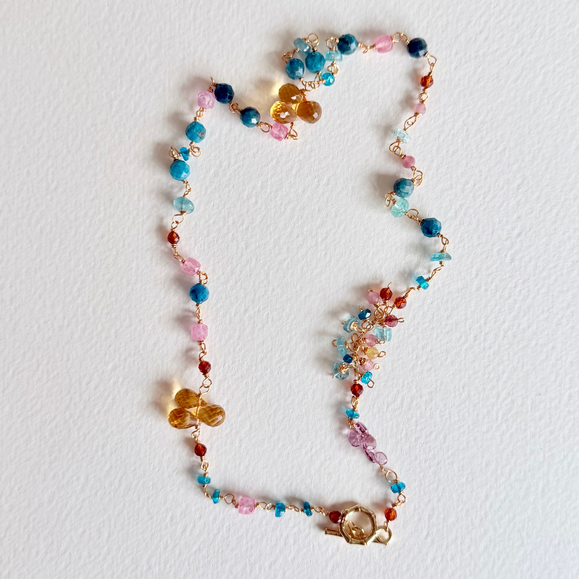 Colorful beaded necklace with floral and butterfly charms on a white background