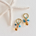 Gold hoop earrings with blue and brown beads on a white surface with starfish
