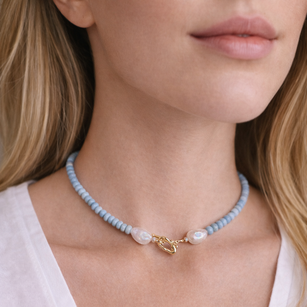 Necklace with blue beads and a gold clasp worn by a model.