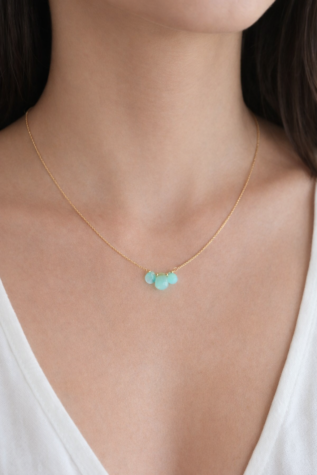 Gold necklace with turquoise beads worn by a person