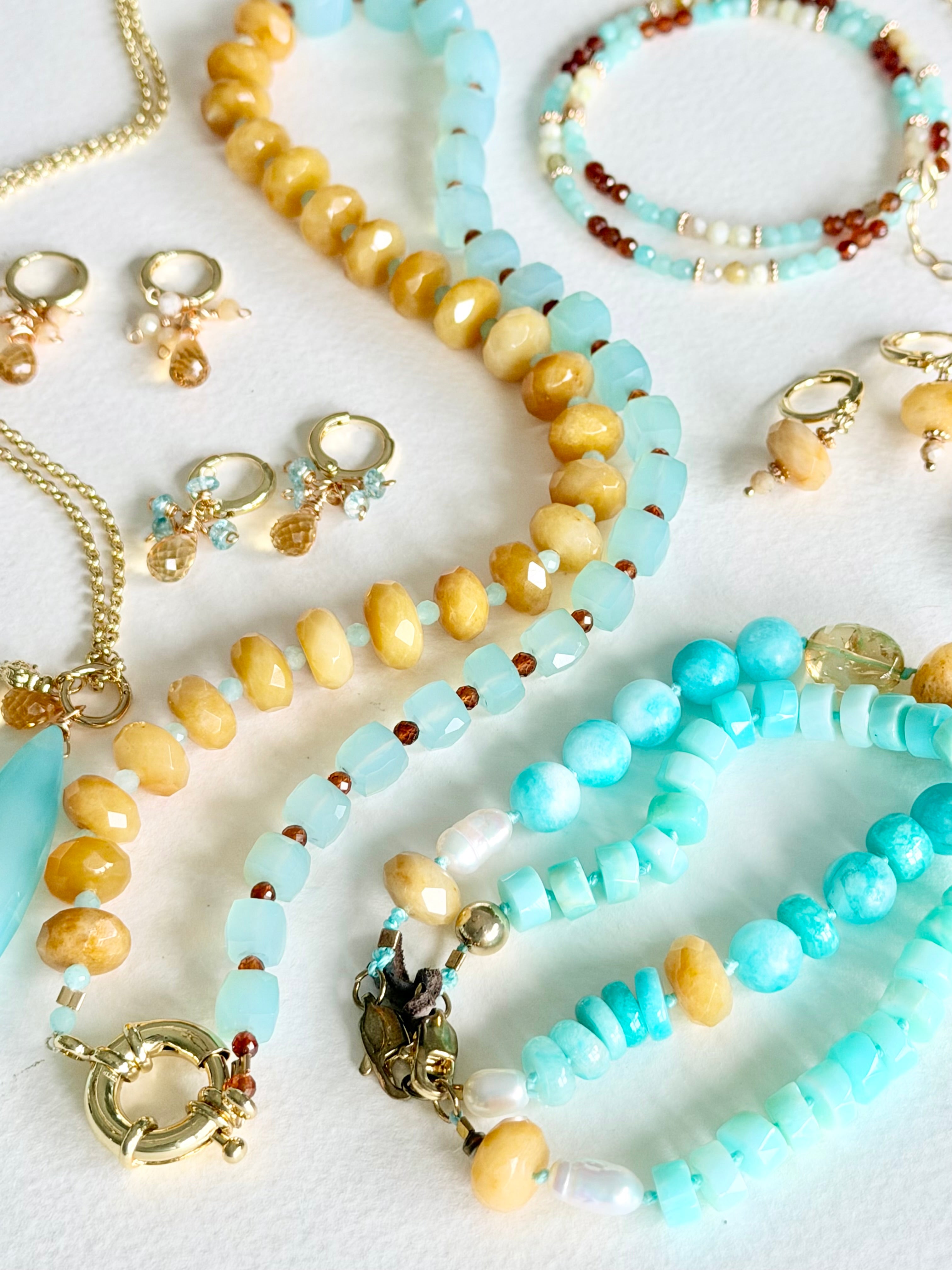 Collection of beaded jewelry including necklaces, bracelets, and earrings on a light background.