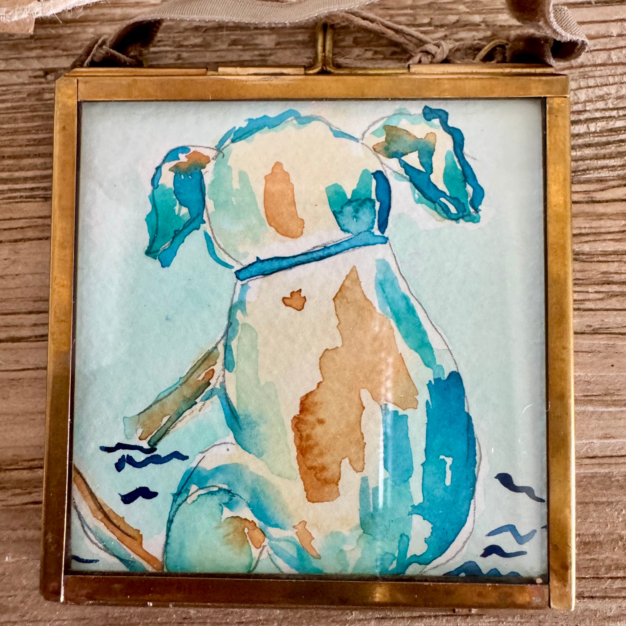 Watercolor of lab dog in yelllow, brown, and blue. Framed in brass square glass frame and tied with brown velvet ribbon to hang as an ornament.