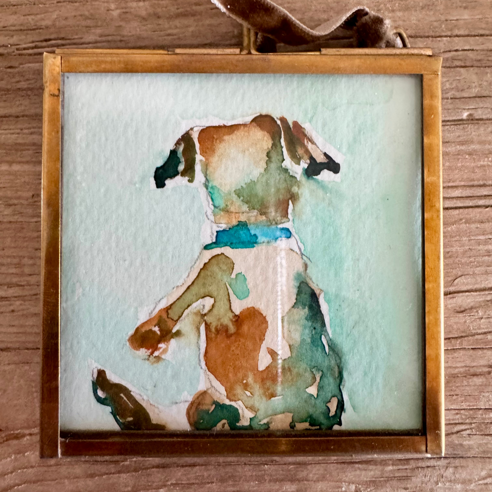 Watercolor of lab dog in brown, blue, and green. Framed in brass square glass frame and tied with brown velvet ribbon to hang as an ornament.