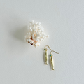 Gold fish-shaped earrings with turquoise stones on a light gray background with white coral.