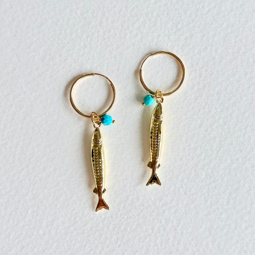 Gold fish-shaped earrings with turquoise beads on a white background