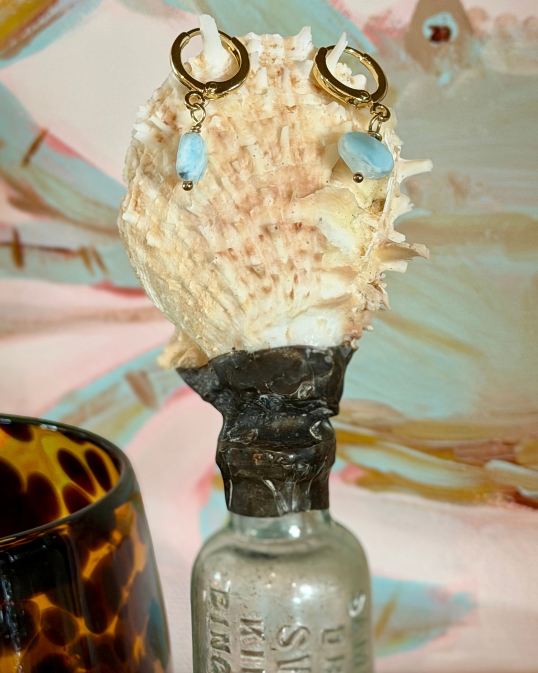 Larimar huggie earrings styled on seashell bottle