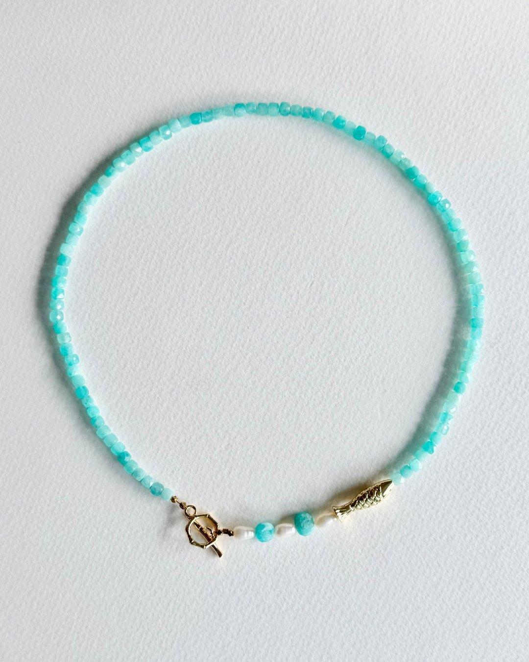 Little Catch Amazonite and freshwater pearl fish necklace laid flat on white background