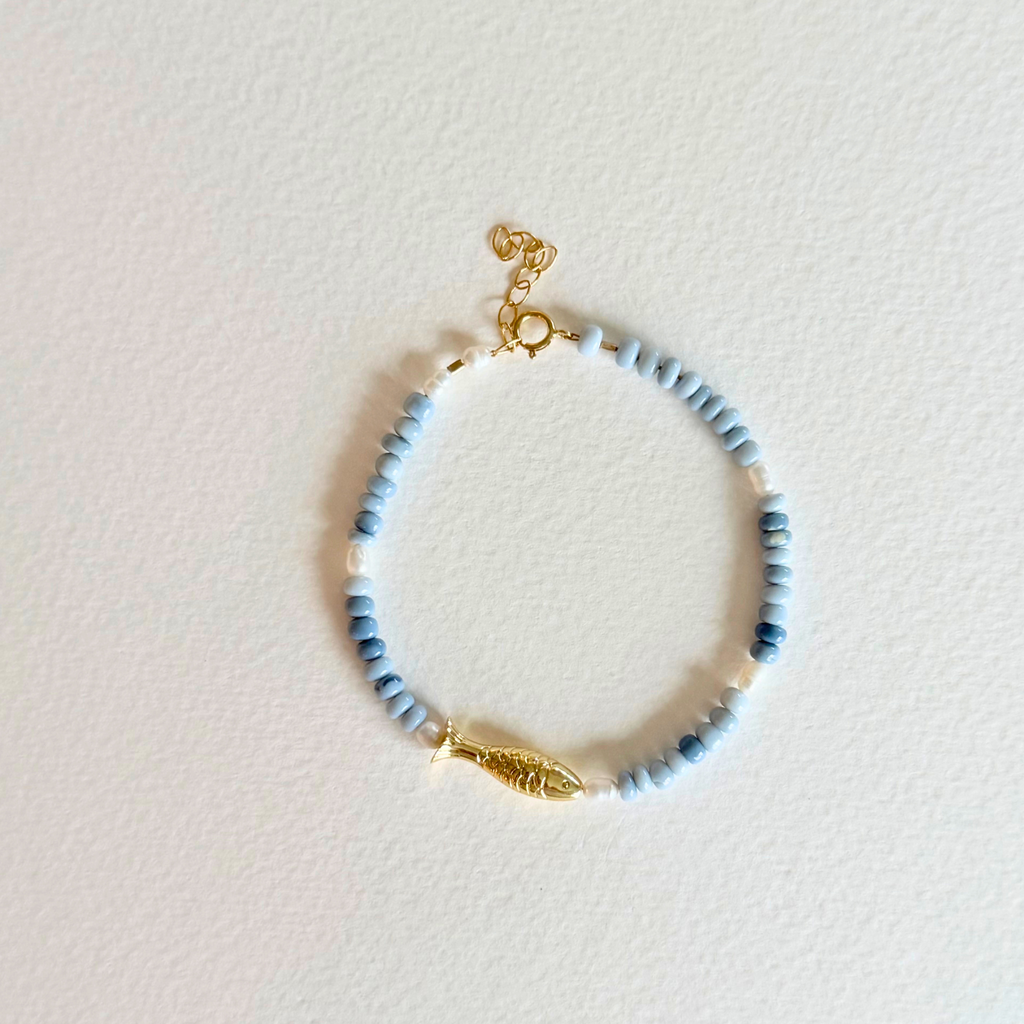 Beaded bracelet with gold accents on a light pink background