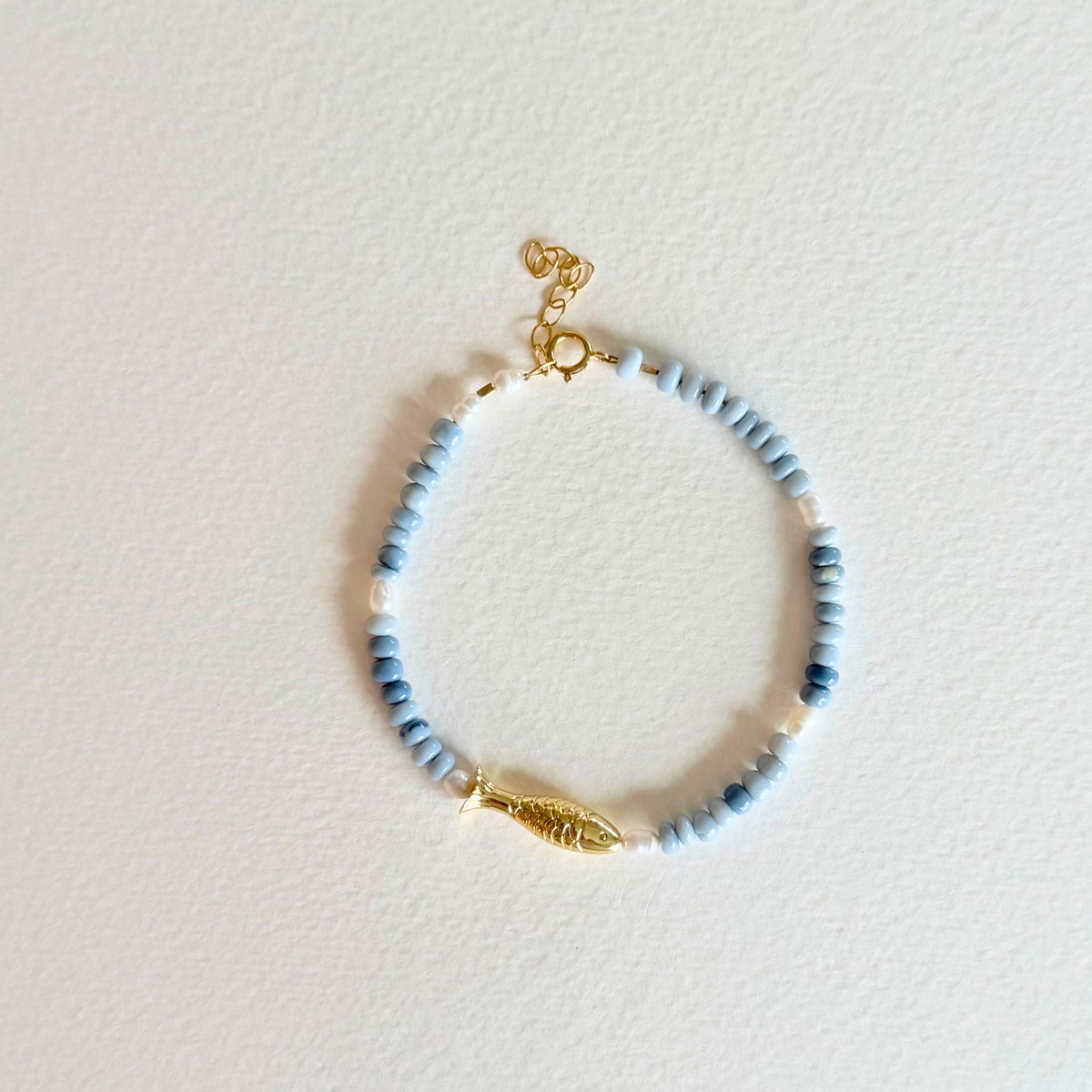 Beaded bracelet with gold accents on a light pink background