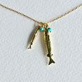 Gold fish-shaped pendant with turquoise beads on a gold chain against a white background