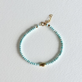 Turquoise beaded bracelet with a gold clasp on a light gray background
